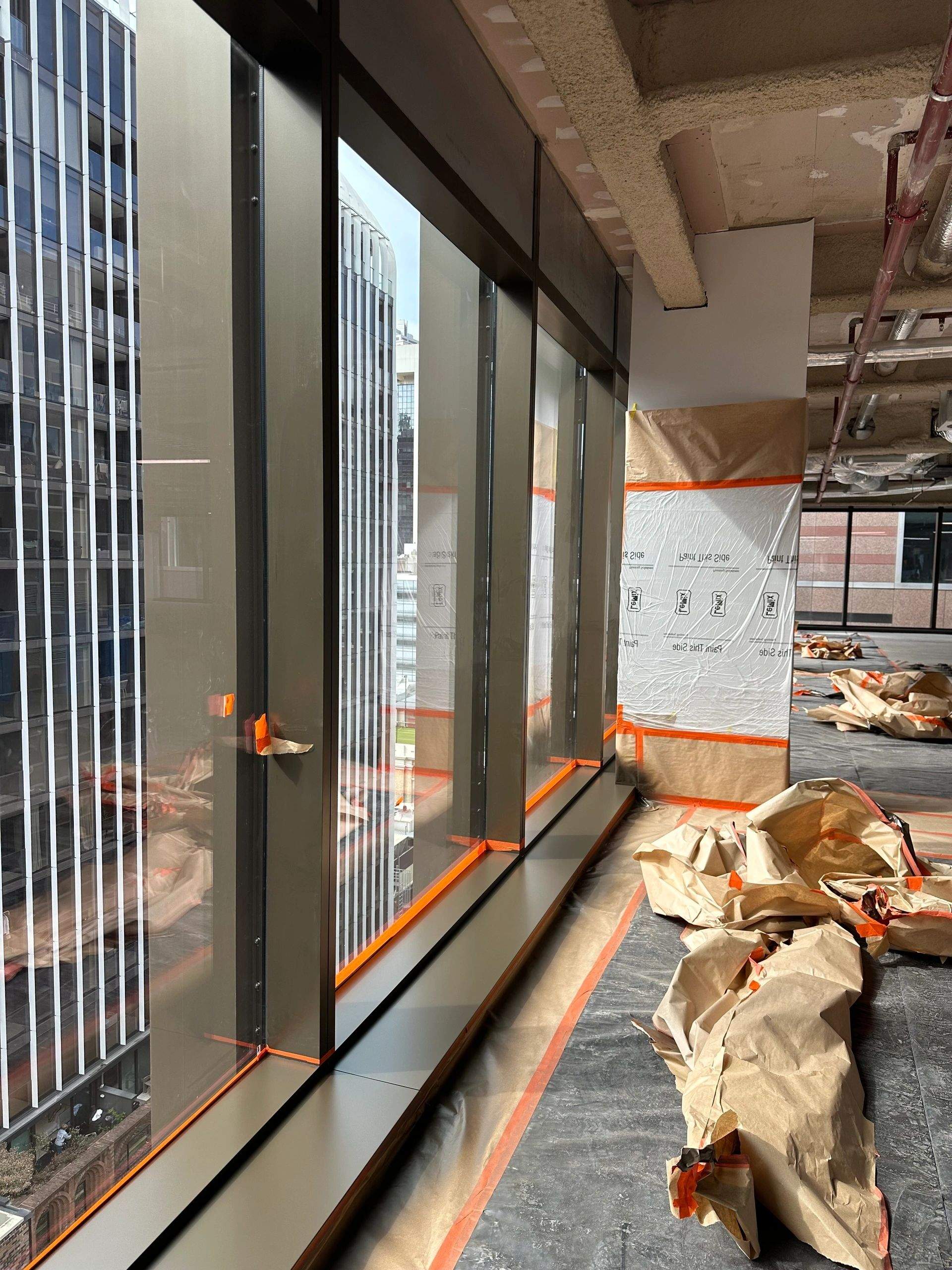 Bronze curtain-wall glazing on a high floor of a Sydney tower, with columns and floors under M&M protection