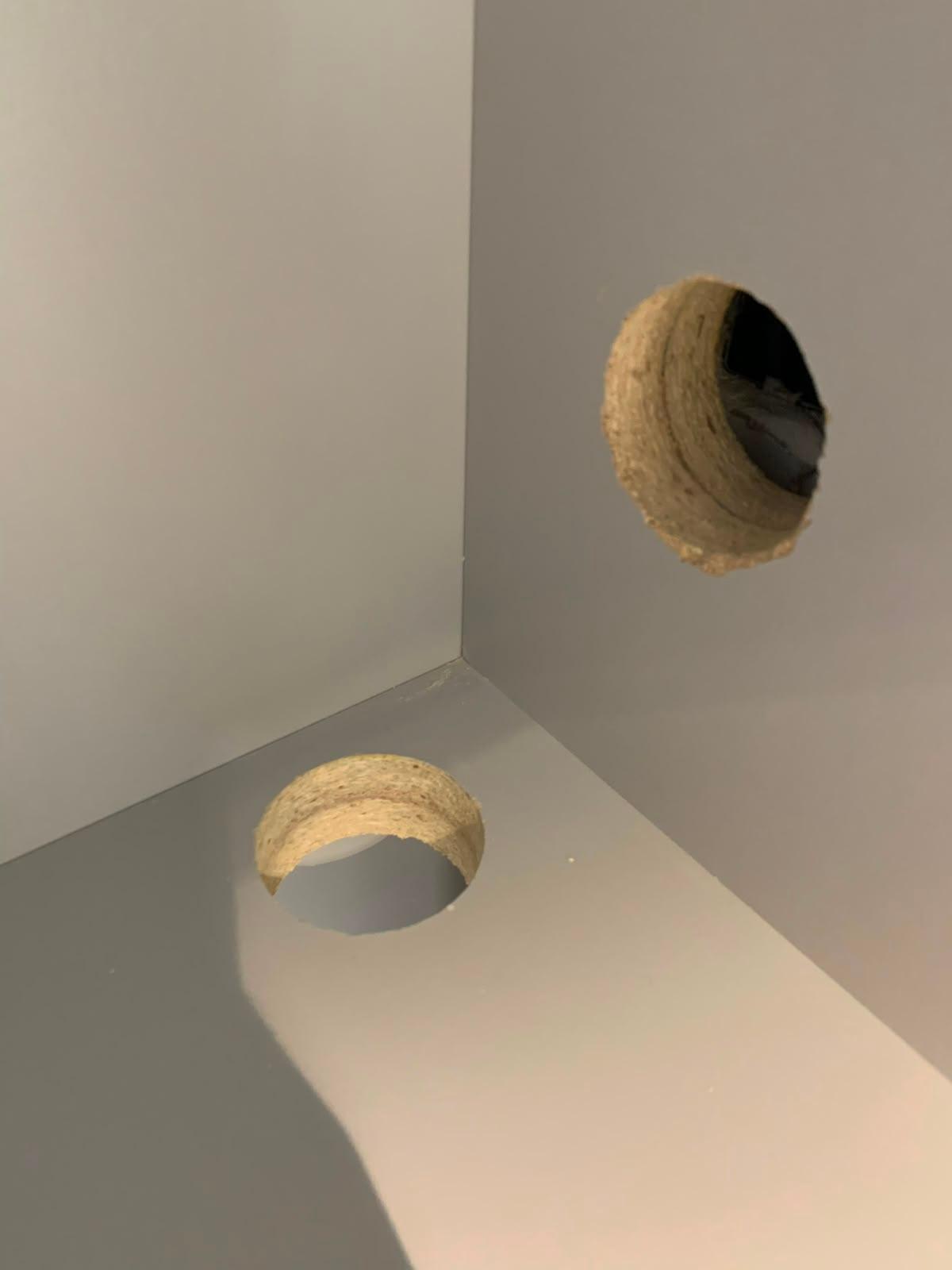 Two open drilled holes in grey joinery